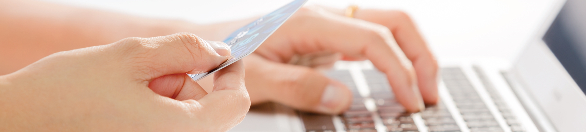 A person entering in credit card information with a credit card in hand